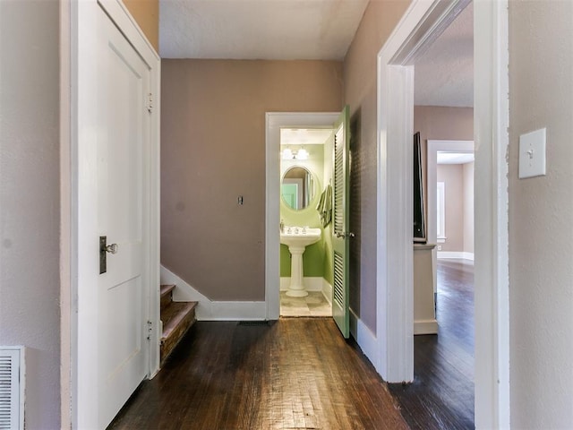 hallway featuring dark wood finished floors, stairs, visible vents, and baseboards