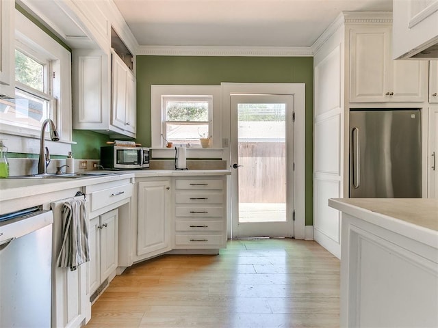 kitchen featuring a sink, stainless steel appliances, light wood-type flooring, and light countertops