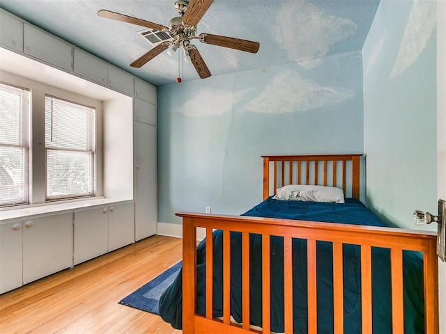 bedroom featuring visible vents, a textured ceiling, wood finished floors, and a ceiling fan