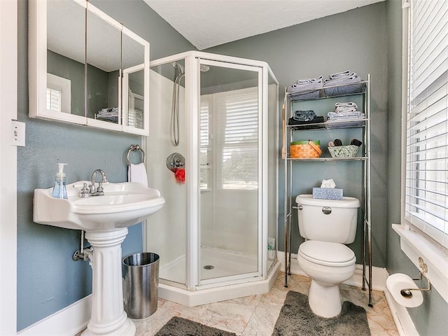 bathroom with baseboards, toilet, and a stall shower