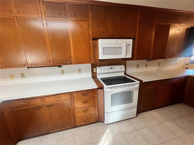 kitchen with light tile patterned flooring, white appliances, and light countertops