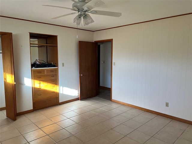 unfurnished bedroom featuring crown molding, baseboards, light tile patterned floors, a closet, and a ceiling fan