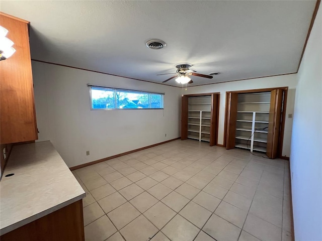 unfurnished bedroom featuring a ceiling fan, light tile patterned floors, baseboards, and visible vents