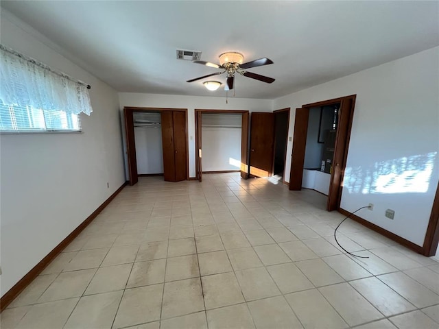 unfurnished bedroom featuring light tile patterned floors, baseboards, visible vents, and two closets