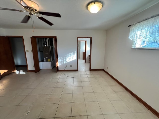 unfurnished room featuring light tile patterned floors, a ceiling fan, and baseboards