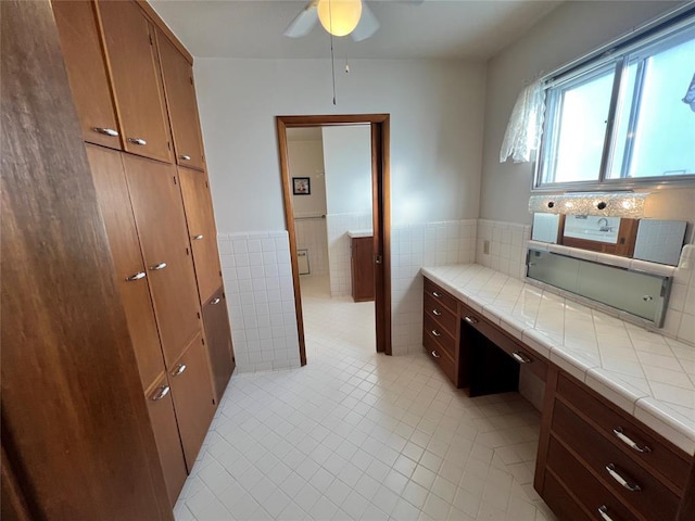 bathroom with tile patterned flooring, wainscoting, tile walls, and ceiling fan