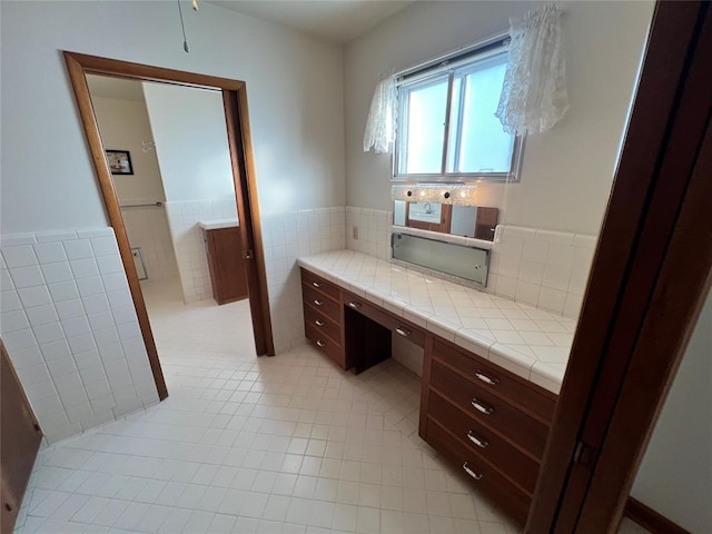 bathroom with a wainscoted wall, tile walls, and tile patterned flooring