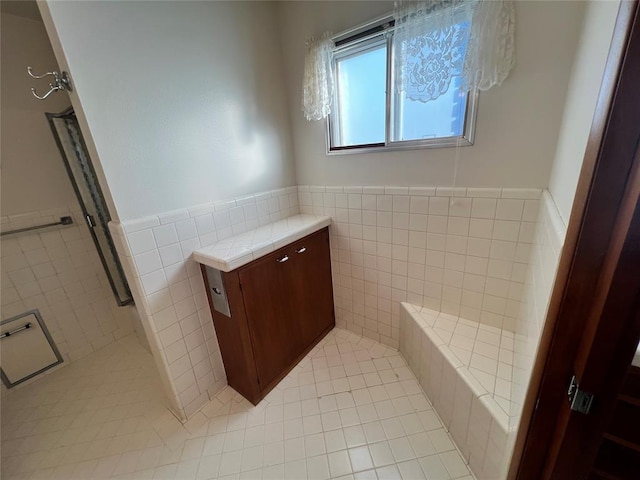 bathroom featuring tile patterned flooring, wainscoting, and tile walls