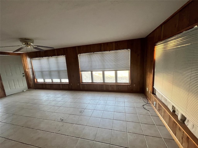 interior space featuring light tile patterned floors, wooden walls, and ceiling fan