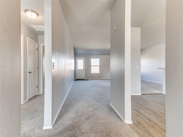 corridor with baseboards, carpet, and a textured wall