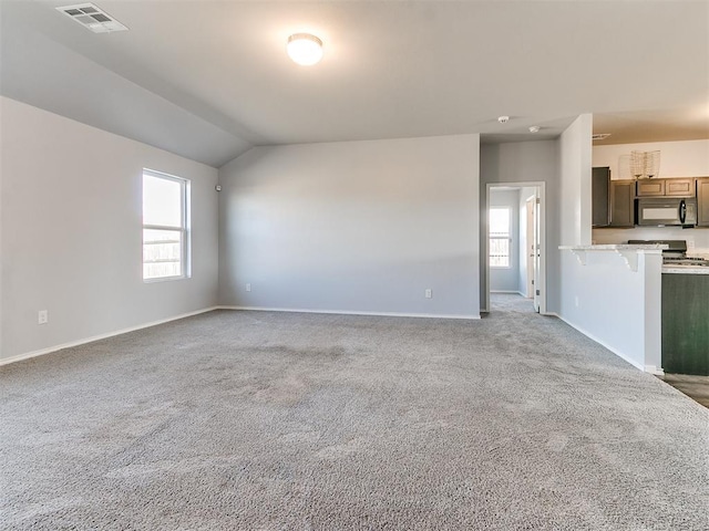 unfurnished living room with lofted ceiling, a healthy amount of sunlight, visible vents, and carpet floors