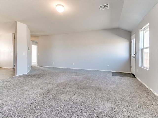 carpeted empty room with vaulted ceiling, baseboards, and visible vents