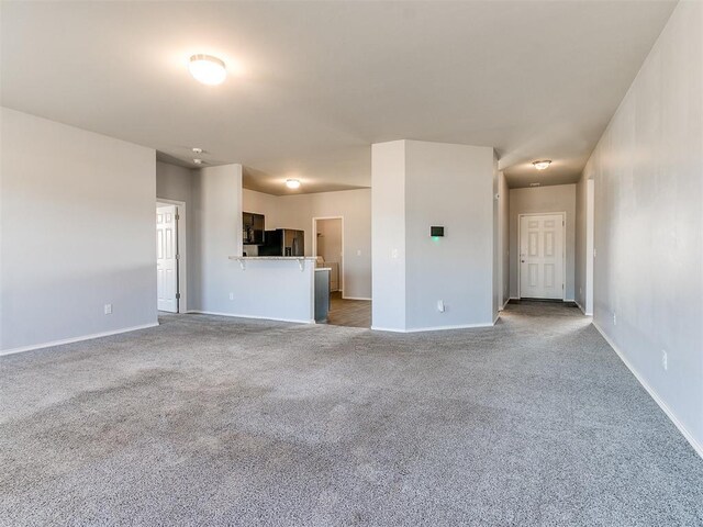 unfurnished living room with carpet and baseboards