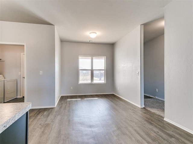 unfurnished dining area featuring baseboards, separate washer and dryer, and wood finished floors