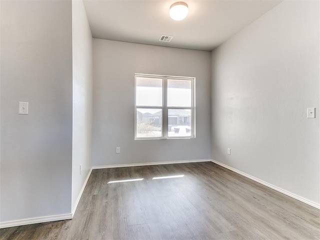 spare room featuring visible vents, baseboards, and wood finished floors