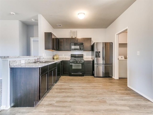 kitchen featuring visible vents, black appliances, light wood-style flooring, washer / clothes dryer, and a sink