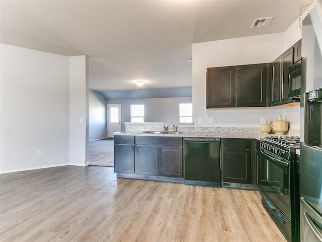 kitchen featuring visible vents, a sink, black appliances, light countertops, and light wood-type flooring