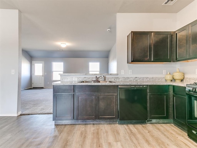 kitchen featuring light stone countertops, light wood-type flooring, a peninsula, black appliances, and a sink