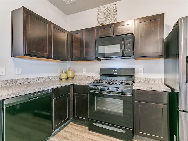 kitchen featuring dark brown cabinets, black appliances, light countertops, and light wood-style floors