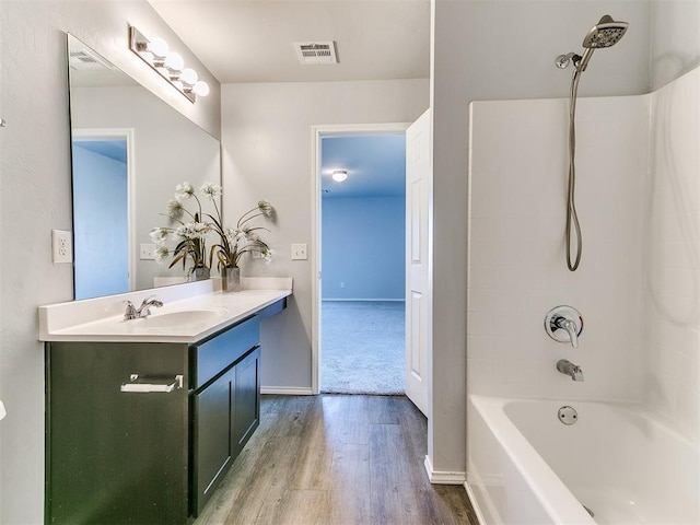 full bathroom featuring visible vents, shower / bath combination, double vanity, wood finished floors, and a sink