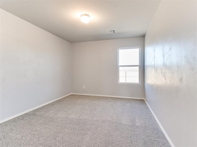 carpeted spare room featuring visible vents and baseboards