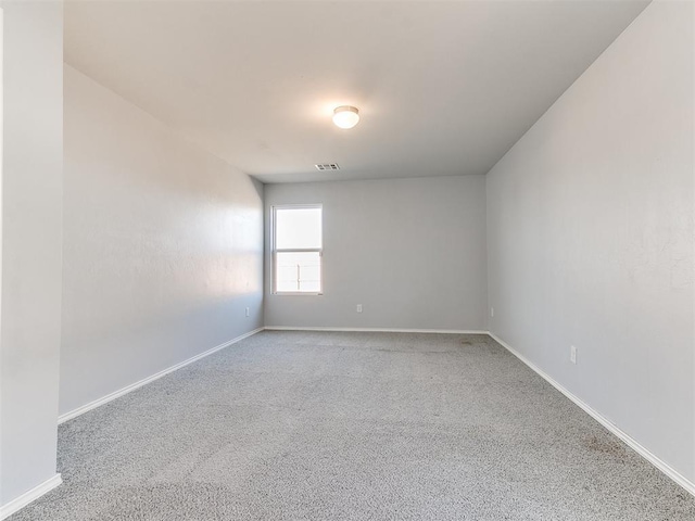 carpeted spare room featuring visible vents and baseboards