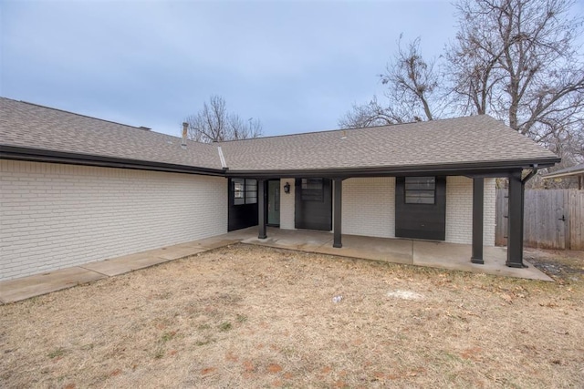 single story home featuring a patio, brick siding, roof with shingles, and fence