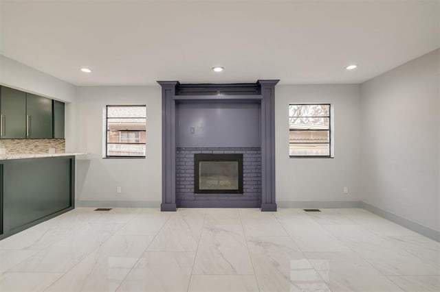 unfurnished living room with visible vents, baseboards, recessed lighting, marble finish floor, and a large fireplace