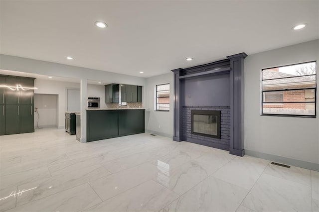 kitchen with visible vents, oven, a large fireplace, green cabinets, and light countertops