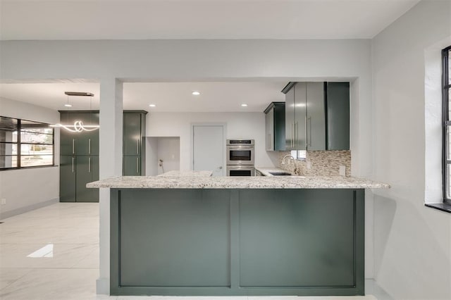 kitchen featuring decorative backsplash, a peninsula, double oven, and light stone counters