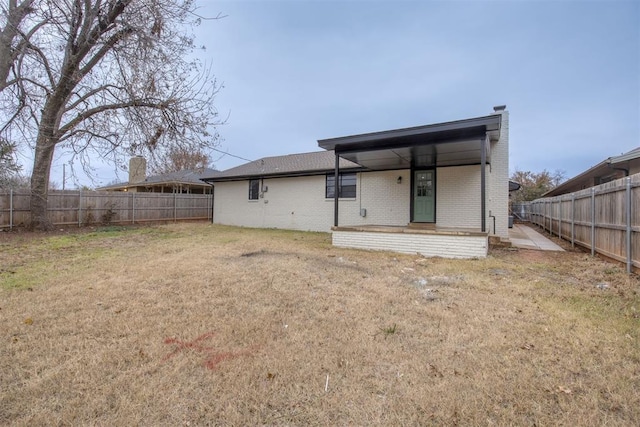 back of property featuring a fenced backyard, brick siding, and a lawn