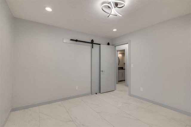 spare room with recessed lighting, a barn door, baseboards, and marble finish floor