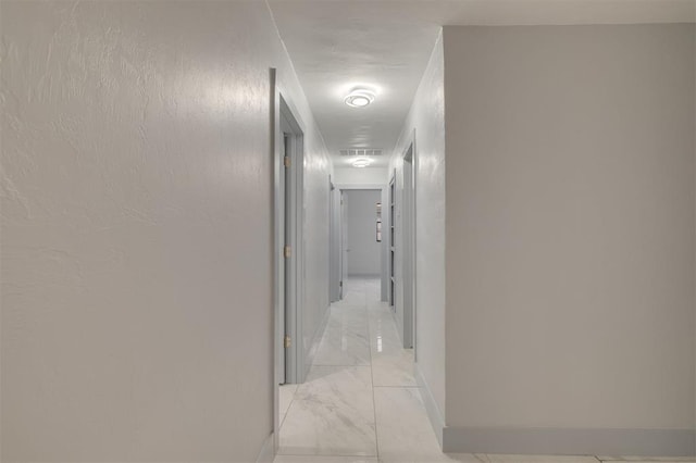 corridor with visible vents, baseboards, and marble finish floor