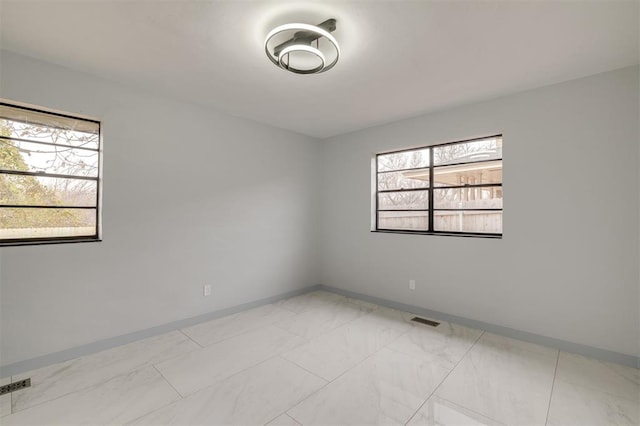 empty room with baseboards, visible vents, and marble finish floor