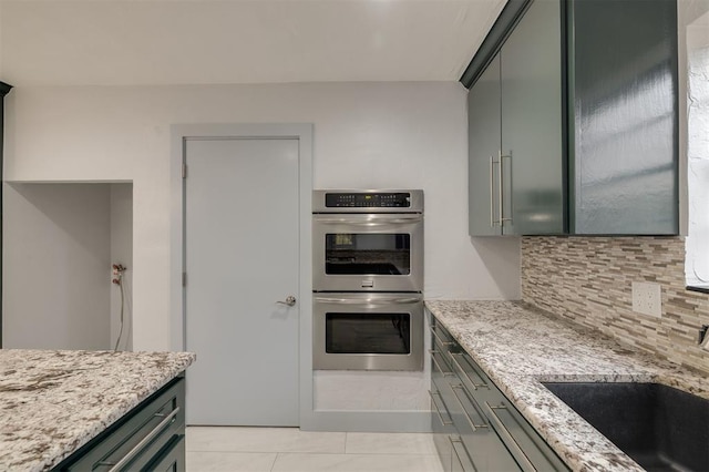 2418 NW 43rd Cir, Oklahoma City, OK 73112 - kitchen featuring stainless steel double oven, light stone counters, light tile patterned floors, a sink, and tasteful backsplash