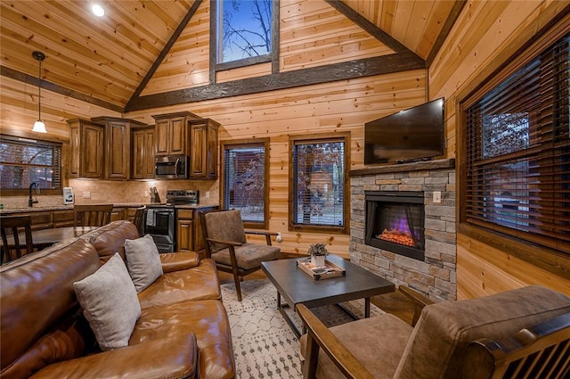 living area featuring wooden walls, wood ceiling, a stone fireplace, and high vaulted ceiling