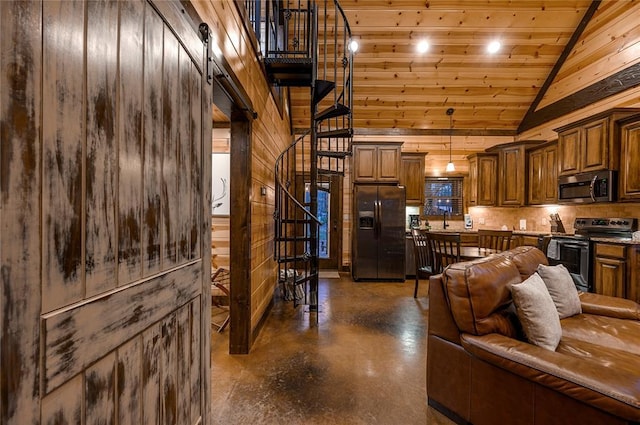 living area featuring stairs, vaulted ceiling, concrete flooring, and wood walls