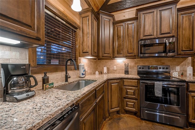 kitchen featuring decorative backsplash, light stone countertops, stainless steel appliances, and a sink