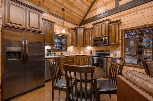 kitchen featuring tasteful backsplash, vaulted ceiling, light stone counters, appliances with stainless steel finishes, and a sink