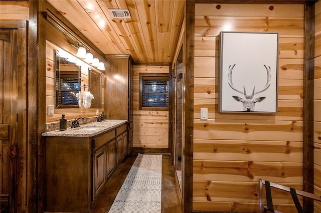 bathroom with wooden ceiling, wooden walls, visible vents, and a sink