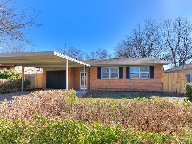 view of front of property with an attached carport, fence, and brick siding