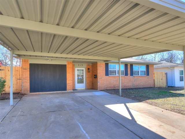 view of front of home featuring an attached carport, brick siding, and fence