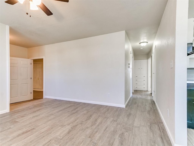 unfurnished room with a ceiling fan, light wood-type flooring, and baseboards