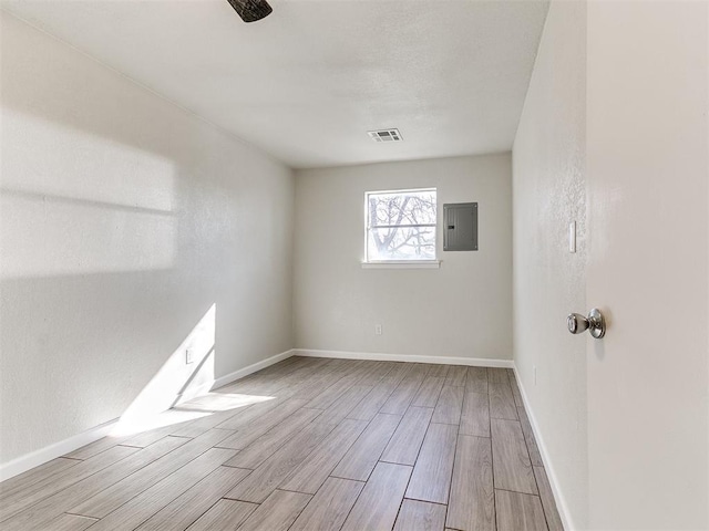 spare room featuring electric panel, visible vents, baseboards, and wood tiled floor