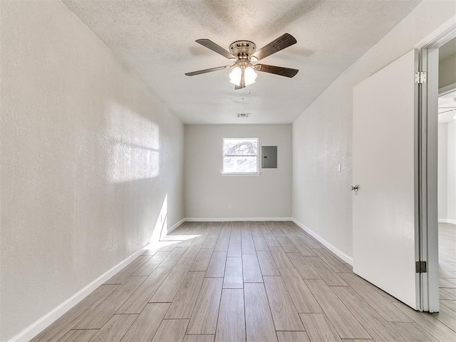 spare room with ceiling fan, baseboards, wood tiled floor, electric panel, and a textured ceiling