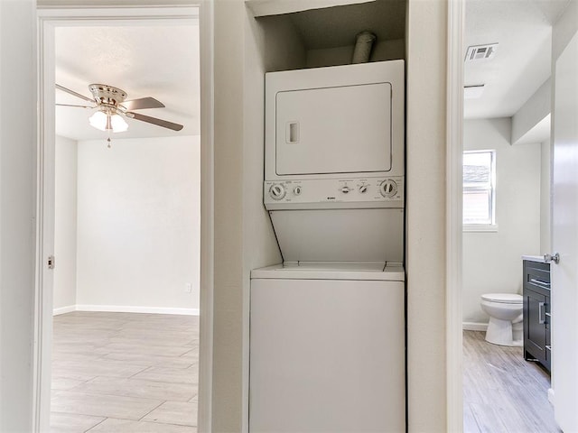 laundry area with visible vents, baseboards, laundry area, stacked washer / drying machine, and a ceiling fan