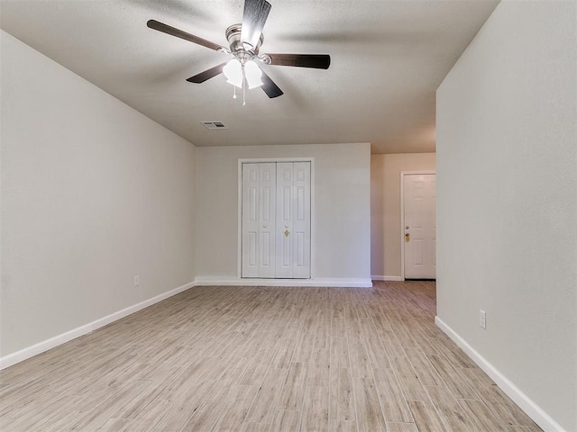 unfurnished bedroom featuring visible vents, ceiling fan, baseboards, light wood-style floors, and a closet