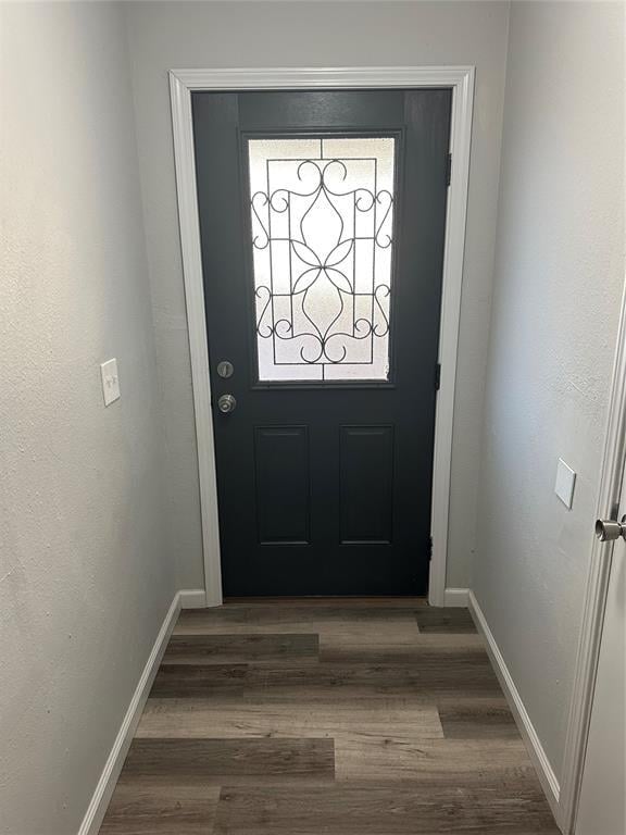 doorway with wood finished floors and baseboards