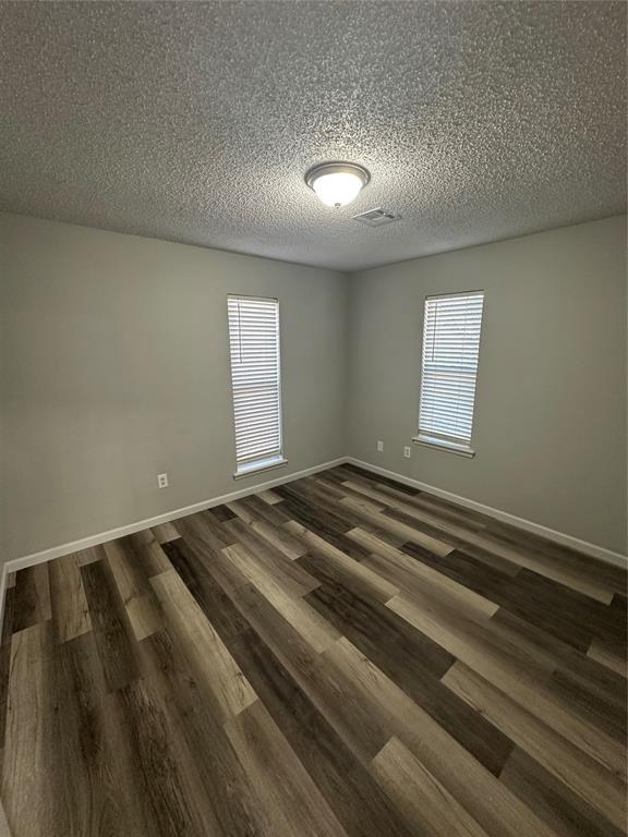 unfurnished room featuring baseboards, a healthy amount of sunlight, and dark wood-style floors