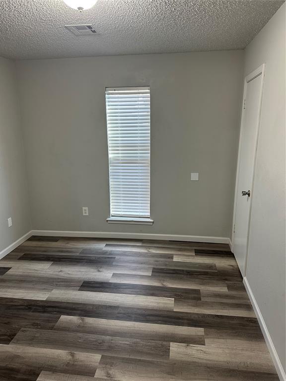 unfurnished room with baseboards, a textured ceiling, and wood finished floors